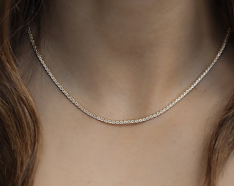 Peut inclure: Un collier délicat en chaîne dorée avec de petites pierres de zircone cubique claires serties en ligne continue.