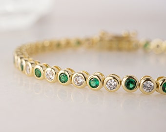 May include: A gold bracelet with alternating round green and white gemstones.