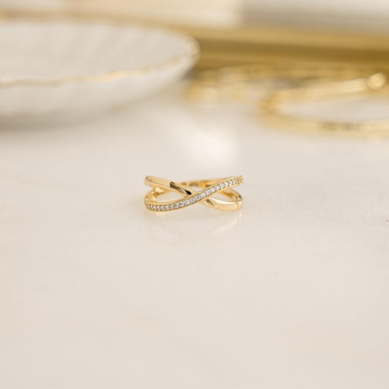 close up of gold wedding band with an X design