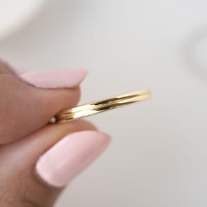 Puede incluir: Un anillo de banda de oro simple con un acabado liso y pulido.