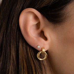 model wearing a gold knot hoop with a stud in the second piercing