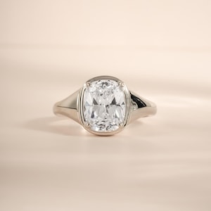 Elongated diamond ring in sterling silver with a bezel-set cushion cut stone.