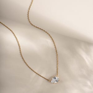 Gold diamond pendant necklace on plain background