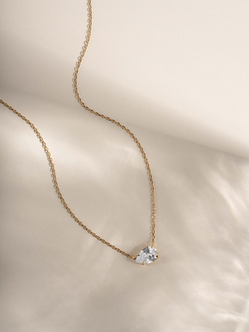 Gold diamond pendant necklace on plain background