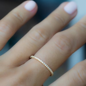 May include: A thin gold band ring with a delicate diamond-like pattern.