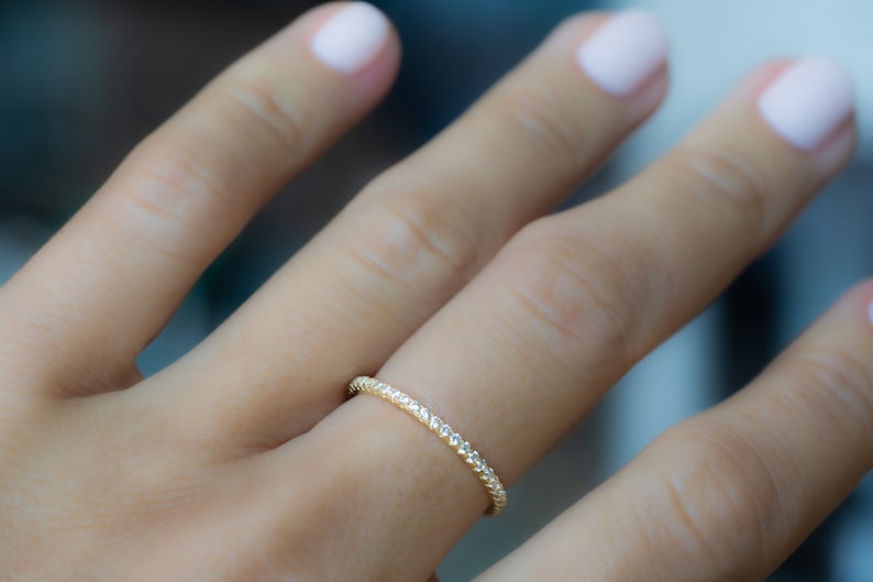 May include: A thin gold band ring with a delicate diamond-like pattern.