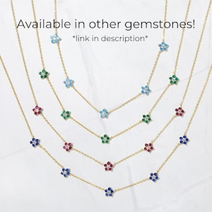 Pu&ograve; includere: Cinque catene d'oro con ciondoli a forma di fiore in diversi colori: blu, verde, rosso e zaffiro. Le catene sono sovrapposte su uno sfondo bianco. *link nella descrizione*