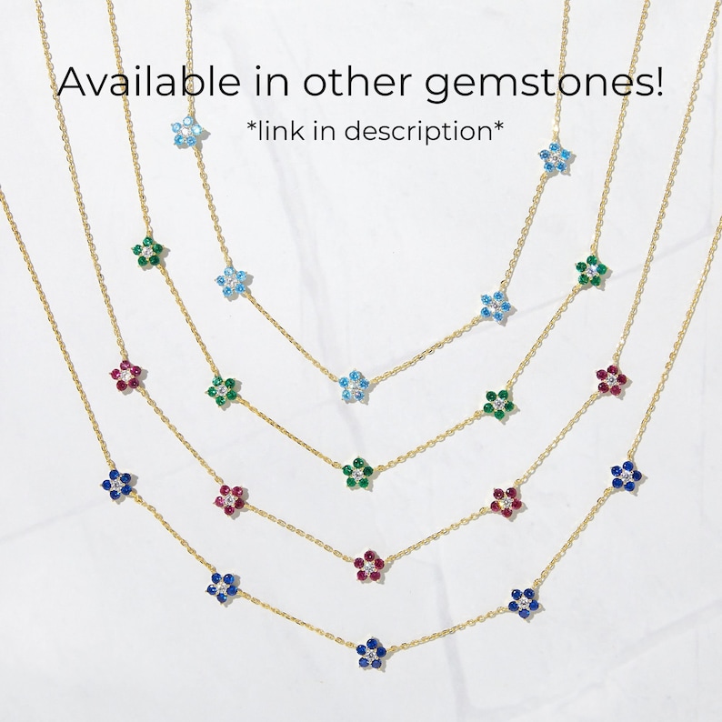 Pu&ograve; includere: Cinque catene d'oro con ciondoli a forma di fiore in diversi colori: blu, verde, rosso e zaffiro. Le catene sono sovrapposte su uno sfondo bianco. *link nella descrizione*