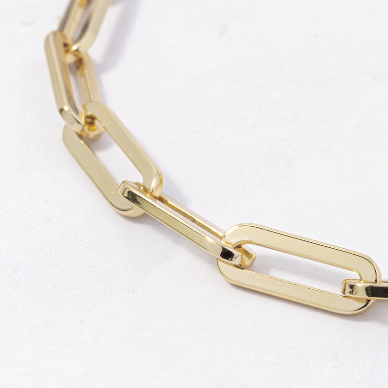 May include: A close-up of a gold chain necklace with a linked, rectangular design.