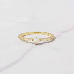 close up image of dainty opal ring with cubic zirconia pave stones on gold band