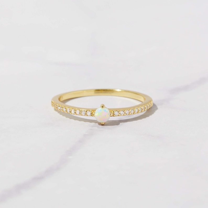 close up image of dainty opal ring with cubic zirconia pave stones on gold band