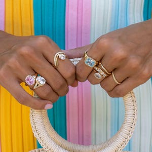 Colored gemstone rings stacked in gold on model