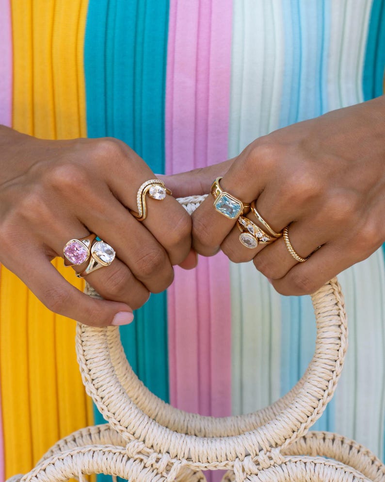 Colored gemstone rings stacked in gold on model