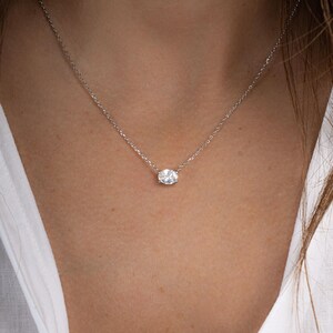 Model wearing silver necklace with oval solitaire necklace
