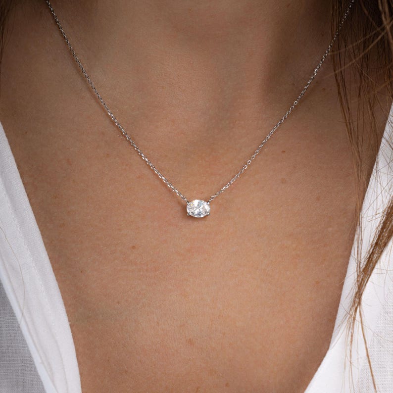 Model wearing silver necklace with oval solitaire necklace