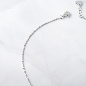 May include: A silver chain necklace with a heart-shaped clasp.