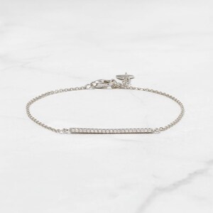 May include: A delicate silver chain bracelet with a thin bar set with small diamonds.