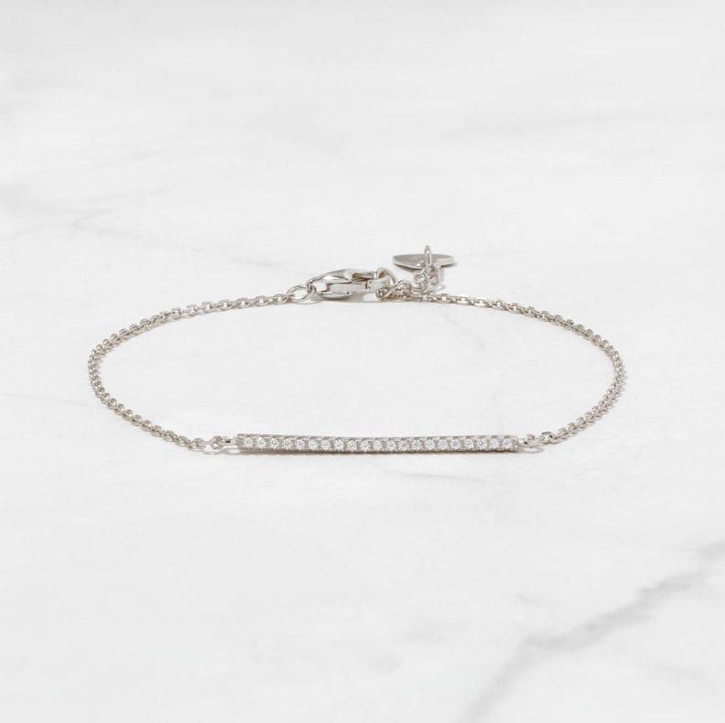 May include: A delicate silver chain bracelet with a thin bar set with small diamonds.
