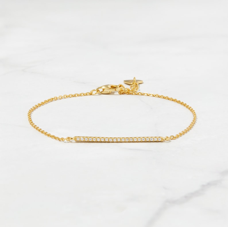 May include: A gold chain bracelet with a thin bar of pave diamonds.