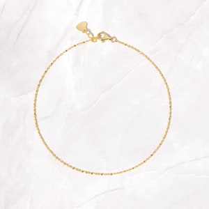 May include: A delicate gold chain anklet with a heart-shaped clasp.