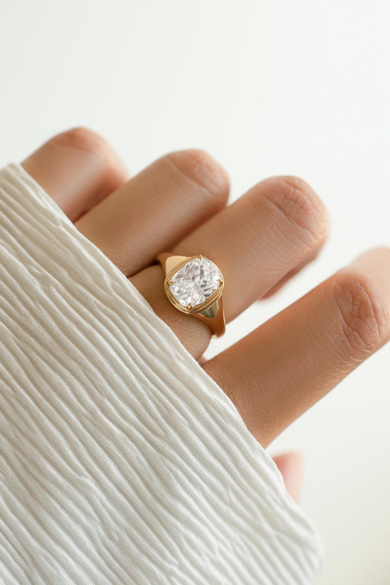 Model image of an elongated diamond cushion cut ring in gold plating worn on models hand