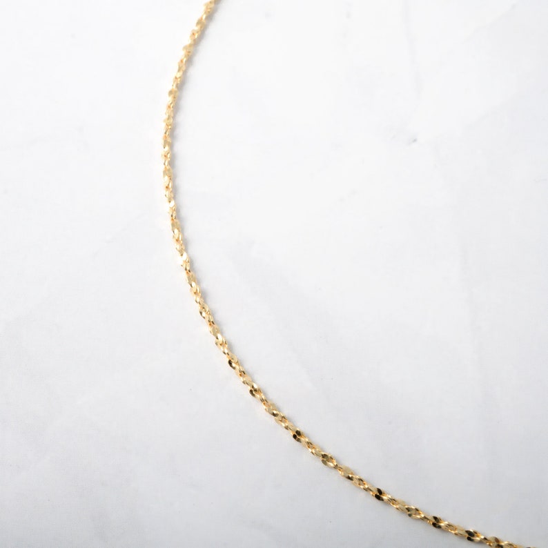 May include: A gold chain necklace with a delicate, twisted design.