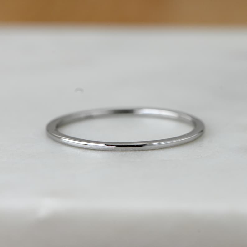 May include: A simple silver band ring with a polished finish.