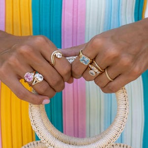 Colored gemstone rings stacked in gold on model