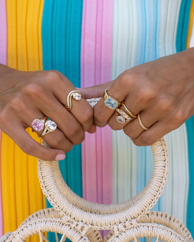 Colored gemstone rings stacked in gold on model