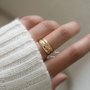 a model wearing two rings, one 3mm wide and another one that is 5mm wide.
