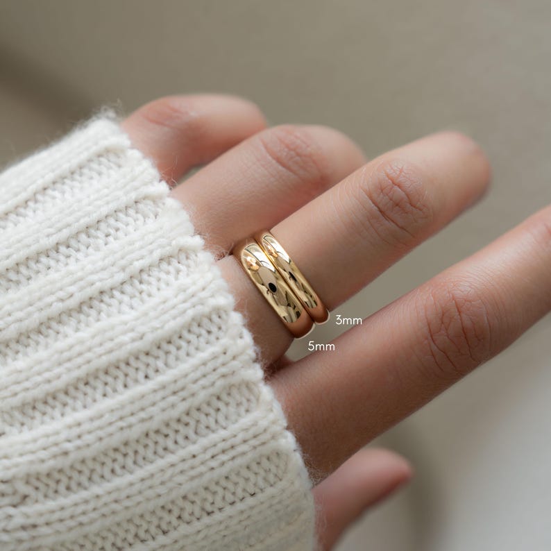 a model wearing two rings, one 3mm wide and another one that is 5mm wide.