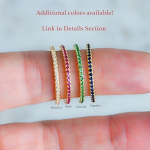 May include: Four gold rings with a single row of gemstones. The rings are lined up from left to right: white CZ, ruby, emerald, and sapphire.