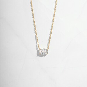 Closeup image of gold necklace with oval solitaire diamond pendant