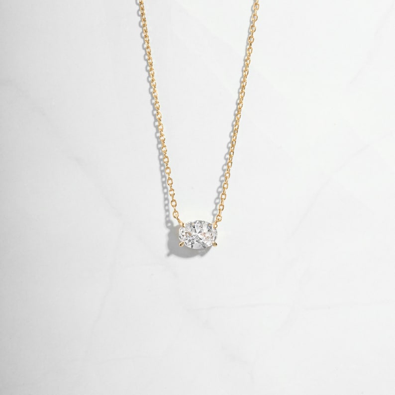 Closeup image of gold necklace with oval solitaire diamond pendant