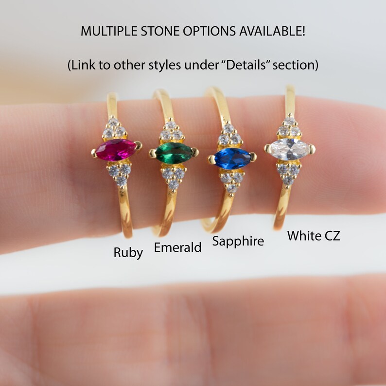 K&ouml;nnte beinhalten: Vier goldene Ringe mit verschiedenen Edelsteinen. Die Ringe haben einen markisenf&ouml;rmigen Edelstein, der von kleineren runden Steinen umgeben ist. Die Edelsteine sind Rubin, Smaragd, Saphir und wei&szlig;er Zirkonia.