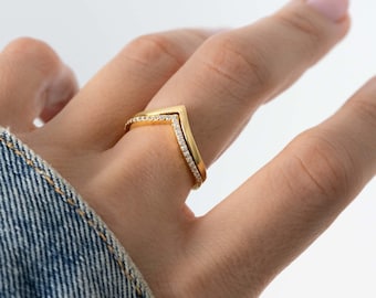 May include: A gold ring with a V-shaped design and small clear stones set along the edges.