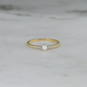 closeup image of october birthstone ring featuring a gold band and cubic zirconia stones