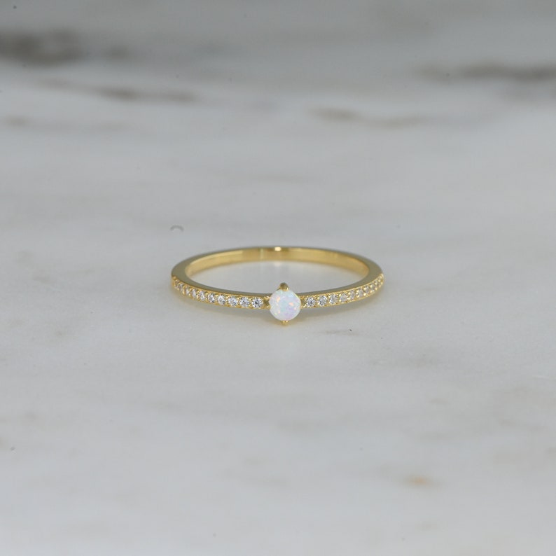 closeup image of october birthstone ring featuring a gold band and cubic zirconia stones