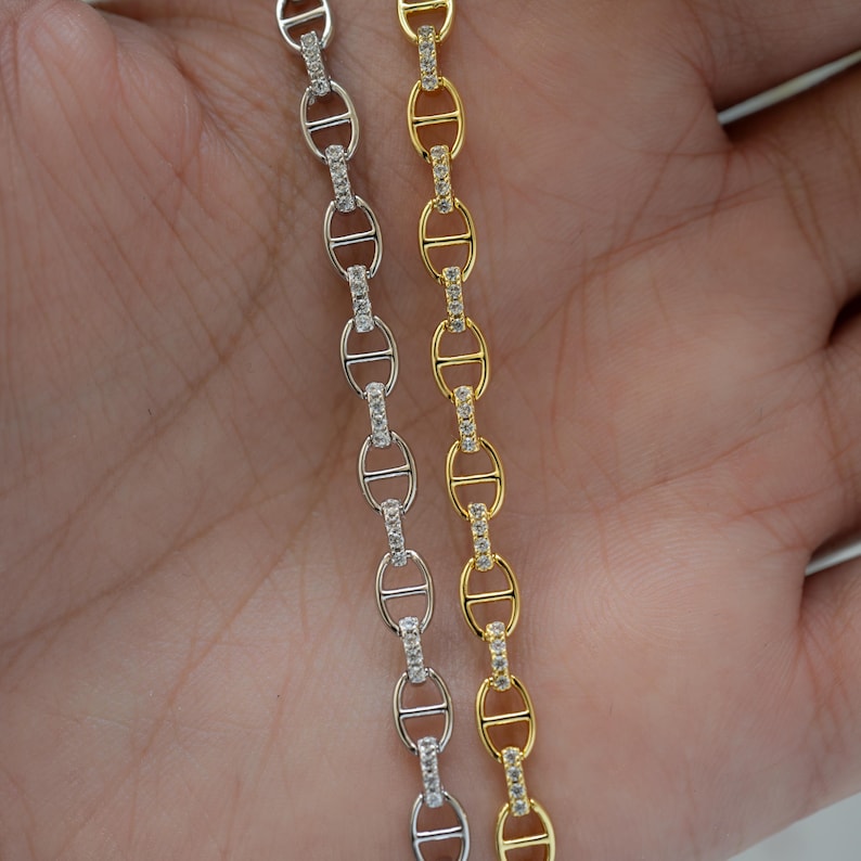 model holding a silver diamond chain bracelet and a gold diamond chain bracelet