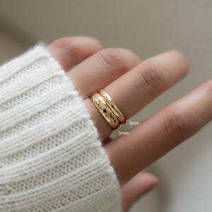 model wearing gold bands shown together to illustrate size differences or can be worn together.