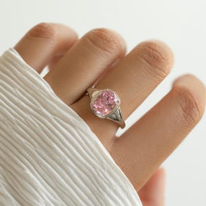 Elongated cushion cut pink ring in sterling silver with a cubic zirconia pink stone, worn on the hand as a statement ring.
