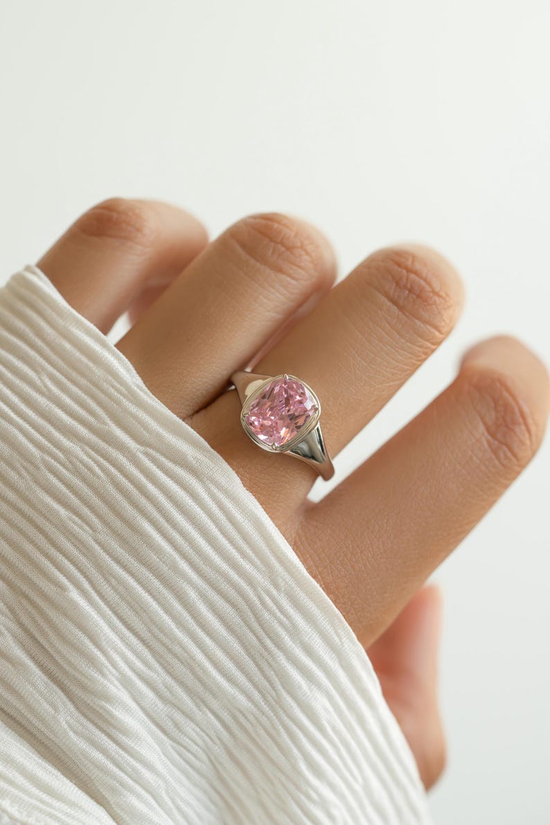 Elongated cushion cut pink ring in sterling silver with a cubic zirconia pink stone, worn on the hand as a statement ring.