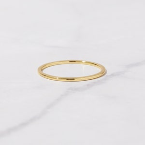 May include: A simple gold band ring. The ring is thin and has a smooth, polished finish.