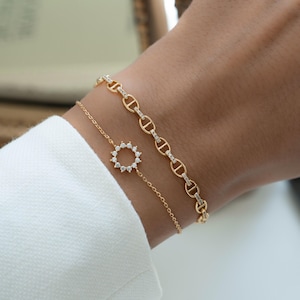 model wearing a sunburst charm bracelet and a dainty chain bracelet