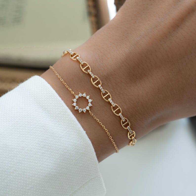 model wearing a sunburst charm bracelet and a dainty chain bracelet