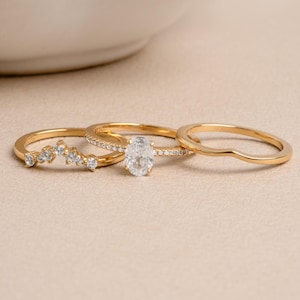 Gold bridesmaid jewelry featuring a gold ring set on a beige background