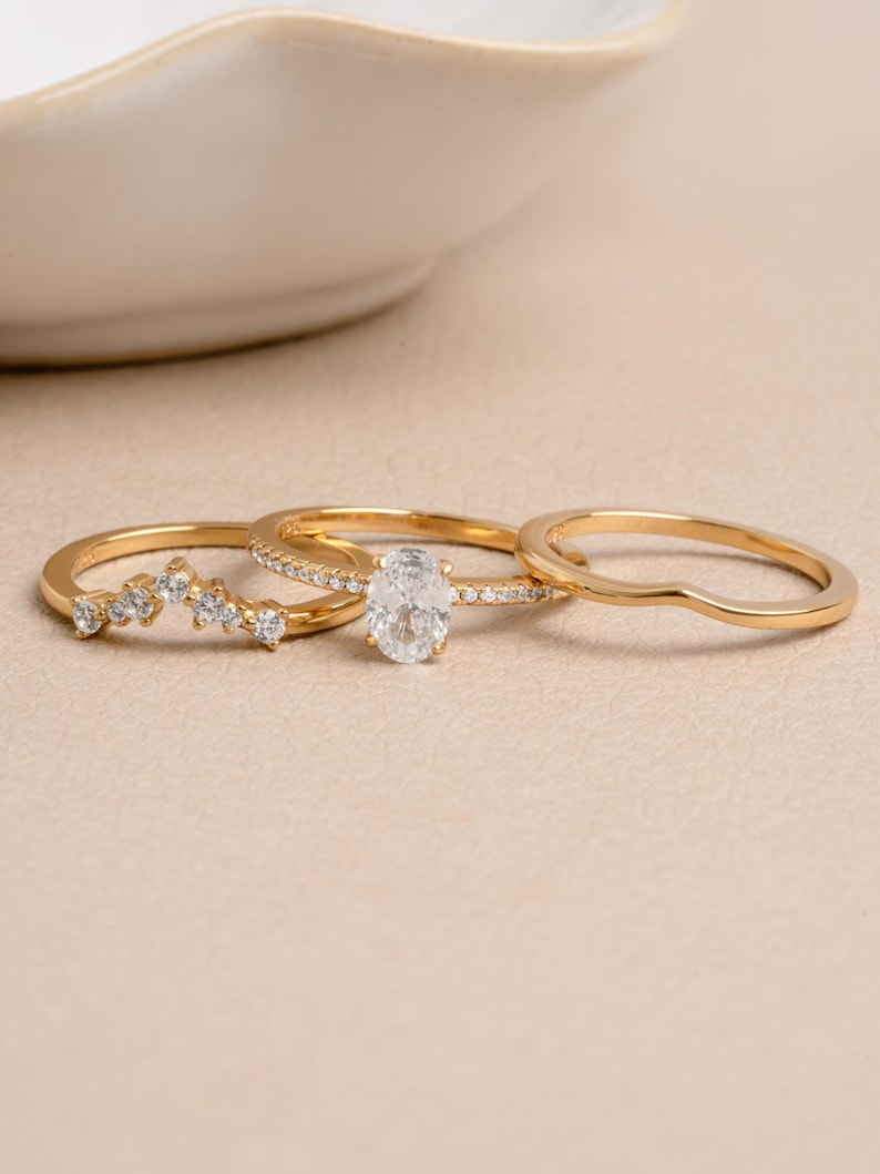 Gold bridesmaid jewelry featuring a gold ring set on a beige background