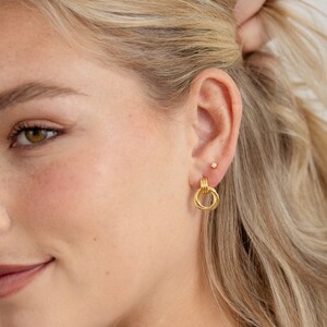 model wearing gold knot hoop earrings