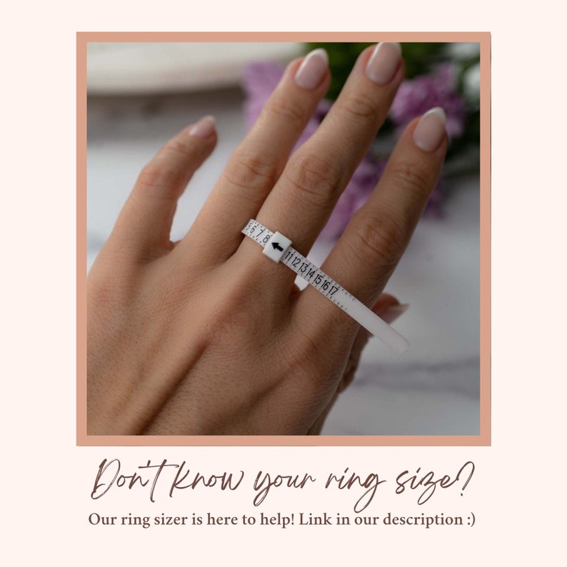 May include: A white plastic ring sizer with numbers 5 through 17 printed on it. The ring sizer is on a person's finger. The text "Don't know your ring size? Our ring sizer is here to help! Link in our description :)" is below the image.