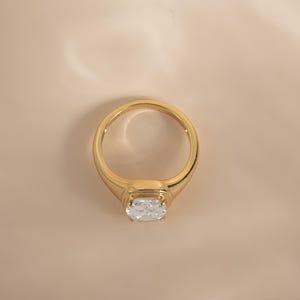 Top-down view of an elongated diamond ring in gold, styled as an engagement ring